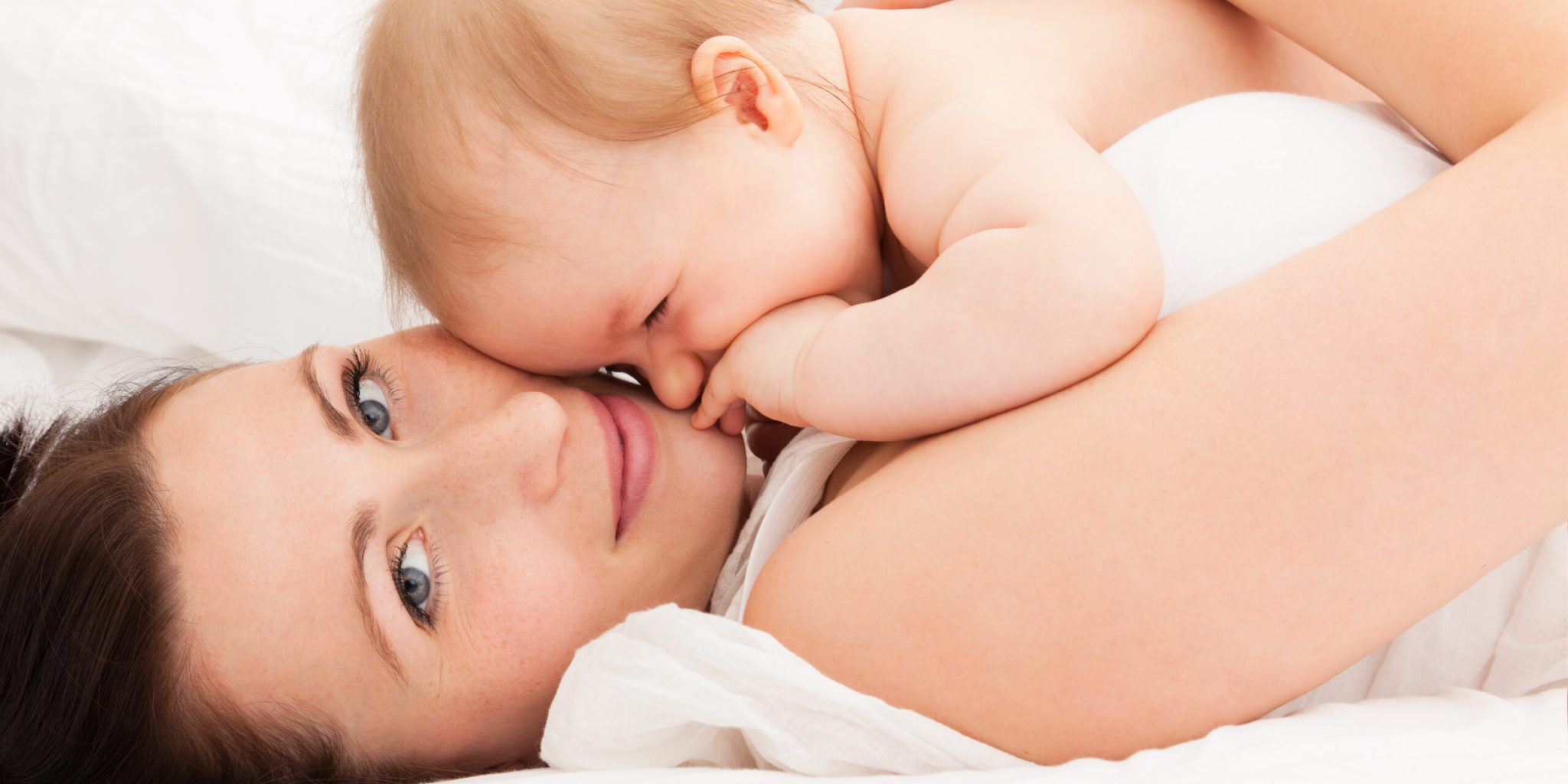 Cute,Embracing,Mother,With,Baby,In,Bed,Enjoying,Time,Together